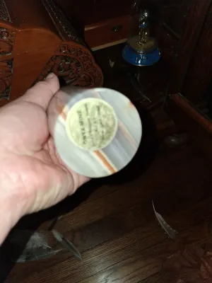 Sale Photo Thumbnail #46: Hand-held view of the bottom of a polished onyx vase, showing an original maker's label.
