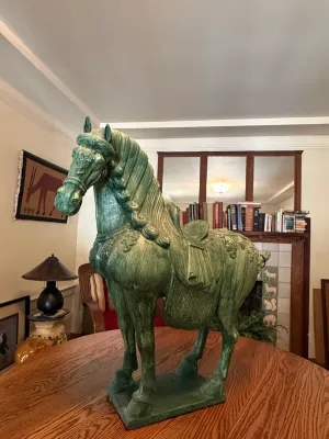 Sale Photo Thumbnail #185: Large green-painted Tang Dynasty-style horse statue with ornate saddle details, displayed on a wooden table.