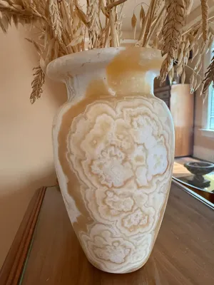 Sale Photo Thumbnail #275: Polished carved onyx or alabaster vase featuring natural white and amber swirling banding, filled with decorative dried wheat stalks.