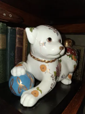 Sale Photo Thumbnail #37: Vintage Japanese porcelain foo dog figurine, decorated with intricate floral and butterfly motifs, gold accents, and resting its paw on a blue ball.