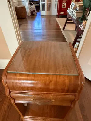 Sale Photo Thumbnail #249: Art Deco style waterfall nightstand featuring a glass-topped surface, single drawer, and an open lower shelf.