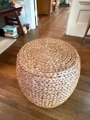 Sale Photo Thumbnail #201: Round woven seagrass or water hyacinth ottoman pouf resting on a hardwood floor.