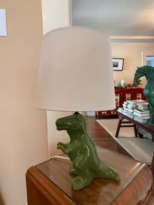 Sale Photo Thumbnail #274: Whimsical green ceramic Tyrannosaurus rex table lamp topped with a neutral drum shade.