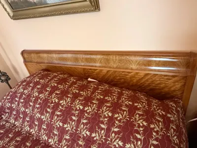 Sale Photo Thumbnail #266: Traditional wooden headboard featuring decorative wood veneer inlays, accompanied by a bed with a burgundy and gold patterned bedspread.