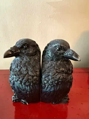 Sale Photo Thumbnail #155: Pair of molded black raven bookends with detailed feather texture and glossy eyes, set on a red surface.