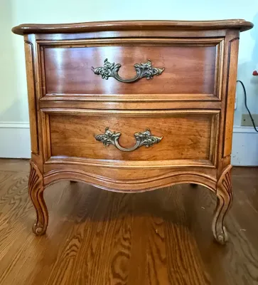 Sale Photo Thumbnail #399: French Provincial style two-drawer wooden nightstand featuring ornate brass pulls and cabriole legs.