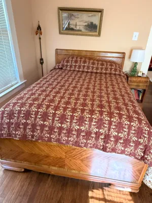 Sale Photo Thumbnail #267: Vintage Art Deco wooden bed frame featuring a matching book-matched veneer headboard and footboard, dressed in a red and gold patterned quilt.