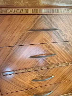 Sale Photo Thumbnail #204: Close-up of a mid-century modern wooden dresser featuring book-matched chevron wood veneer and sleek metal drawer pulls.