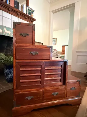 Sale Photo Thumbnail #181: Japanese-style step chest (kaidan tansu) featuring dark stain finish, decorative metal corner braces, sliding slatted doors, and multiple small drawers.