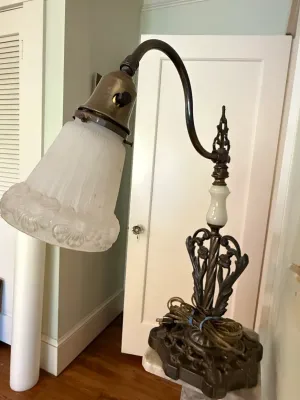 Sale Photo Thumbnail #344: Vintage metal gooseneck bridge arm desk lamp featuring a cast ornate base, milk glass accent piece, and a frosted glass shade with raised floral motifs.