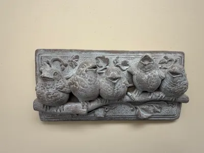 Sale Photo Thumbnail #420: Cast resin or concrete relief wall plaque depicting five birds perched on a branch, featuring a weathered stone-like finish.