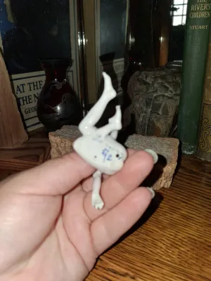 Sale Photo Thumbnail #68: Small vintage porcelain bisque acrobatic figure featuring a hand-painted or stamped mark on its torso.