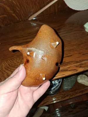 Sale Photo Thumbnail #29: Underside of a vintage glazed ceramic stingray figurine or dish, showing three pointed feet and a textured woven finish.