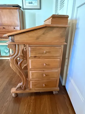 Sale Photo Thumbnail #314: Vintage carved wooden Davenport desk with a slanted writing surface, four side drawers, and ornate scrollwork legs.