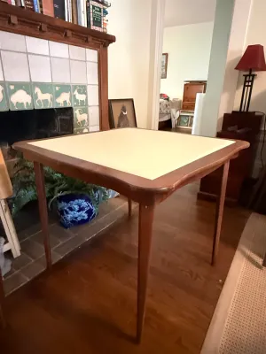 Sale Photo Thumbnail #244: Mid-century modern folding card table with tapered wood legs and a light-colored inset vinyl top.