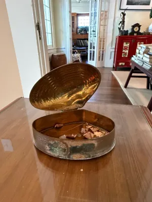 Sale Photo Thumbnail #278: Vintage hinged brass clam shell trinket box containing small natural seashells, displaying light patina and age-appropriate wear.