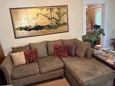 Sale Photo Thumbnail #215: Brown microfiber L-shaped sectional sofa with accent pillows, placed beneath a large framed Japanese four-panel gold leaf folding screen painting.