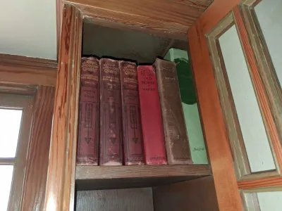 Sale Photo Thumbnail #95: Collection of antique hardcover books, including several volumes of The Junior Classics, arranged on a wooden cabinet shelf.