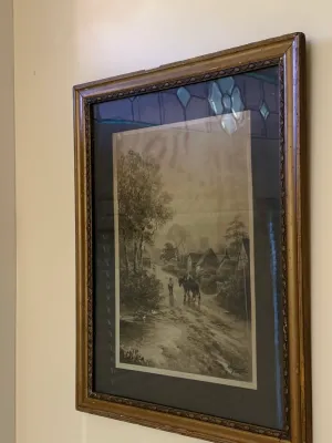 Sale Photo Thumbnail #404: Framed black-and-white landscape print depicting a rural scene with horses and figures, set in a gilded wooden frame with a dark mat.