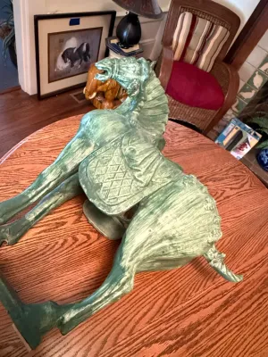 Sale Photo Thumbnail #183: Large Tang dynasty-style ceramic horse sculpture with a distressed green glaze finish, resting on a wooden tabletop.