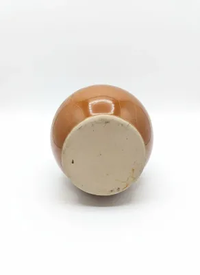 Sale Photo Thumbnail #67: Underside of a vintage ceramic vase with an unglazed stoneware base and a glossy light brown crackle-glazed body.