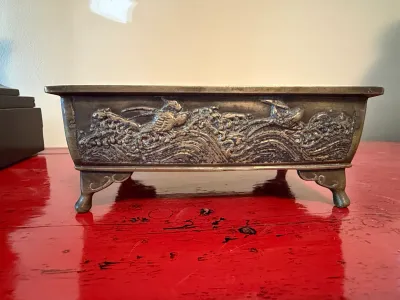 Sale Photo Thumbnail #144: Vintage Japanese embossed metal bonsai planter, featuring relief details of birds and crashing waves on cabriole-style feet.