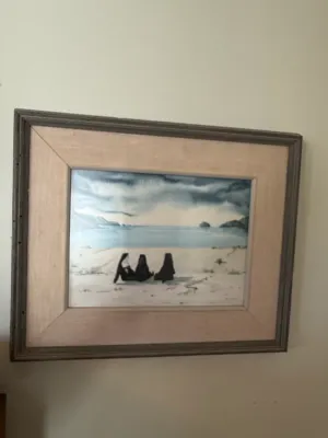 Sale Photo Thumbnail #298: Framed original watercolor painting depicting three figures on a beach under a moody, overcast sky, presented in a wide wooden frame with matting.