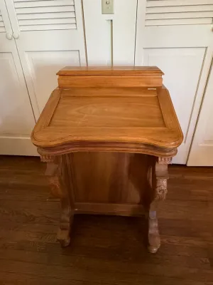Sale Photo Thumbnail #321: Antique carved wooden slant-top clerk's desk featuring detailed floral side supports and a upper compartment.