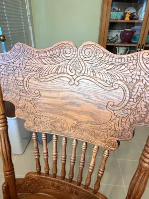 Sale Photo Thumbnail #411: Antique press-back oak dining chair featuring intricate scrollwork and leaf carvings on the crest rail.