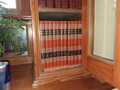 Sale Photo Thumbnail #92: Vintage Childcraft hardcover book set housed inside a wooden cabinet with a glass door.