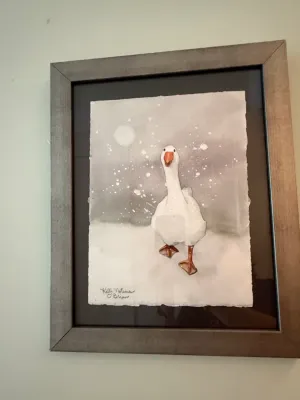 Sale Photo Thumbnail #264: Framed original watercolor painting depicting a goose in a snowy landscape, signed by artist Kelli Nutman O'Brien. Presented in a modern metallic silver frame with float mounting on a dark matboard.
