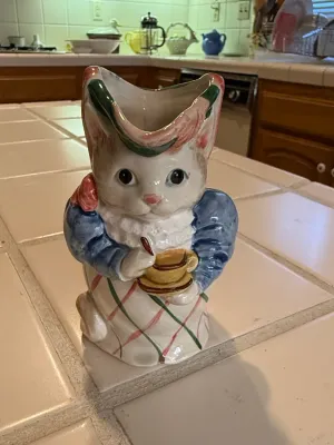 Sale Photo Thumbnail #488: Vintage ceramic anthropomorphic cat pitcher or vase, depicting a cat wearing a bonnet and apron while holding a teacup.