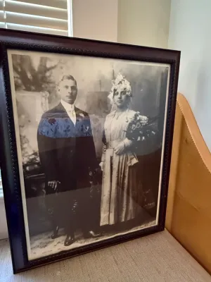 Sale Photo Thumbnail #370: Framed antique black and white wedding portrait of a bride and groom, housed in a dark wood frame with beaded detail.