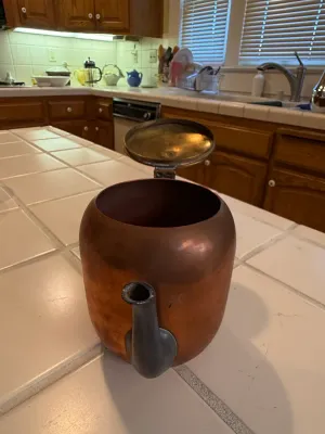 Sale Photo Thumbnail #450: Vintage copper teapot with a dark metallic spout and hinged brass lid, showing age-appropriate patina.