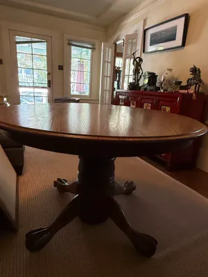 Sale Photo Thumbnail #162: Antique oak pedestal dining table featuring carved claw feet and a glossy polished top.