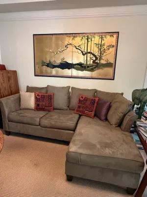 Sale Photo Thumbnail #216: Contemporary taupe microfiber L-shaped sectional sofa with decorative accent pillows, set beneath a large framed Asian-style gold leaf folding screen artwork.