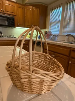 Sale Photo Thumbnail #445: Handcrafted woven wicker basket featuring a prominent bentwood handle, ideal for gatherings or decorative storage.