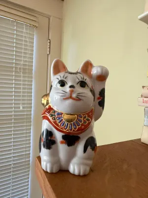 Sale Photo Thumbnail #428: Vintage ceramic Maneki-neko (beckoning cat) figurine featuring hand-painted details and gilded gold accents.
