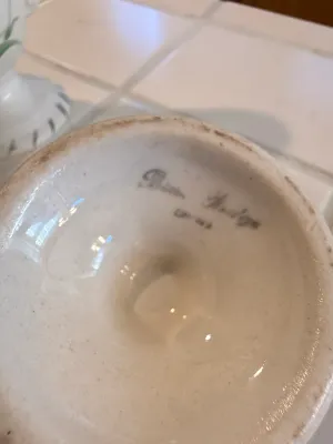 Sale Photo Thumbnail #433: Underside of a vintage ceramic vase showing an artist signature in cursive.
