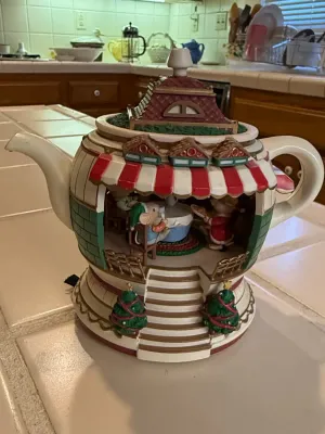 Sale Photo Thumbnail #492: Novelty Christmas teapot-shaped musical box or figurine featuring an interior scene with mice sitting at a dining table.