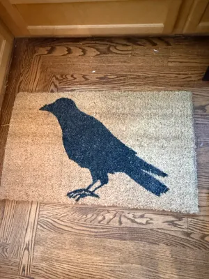 Sale Photo Thumbnail #360: Natural coir doormat featuring a printed black crow or raven silhouette.