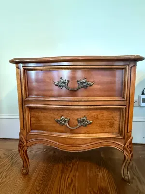 Sale Photo Thumbnail #396: French Provincial style wooden nightstand featuring two drawers with ornate brass bail handles and cabriole legs.