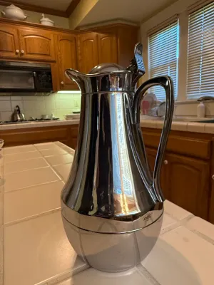 Sale Photo Thumbnail #434: Vintage Alfi chrome-plated insulated thermal coffee carafe pitcher sitting on a tiled kitchen counter.