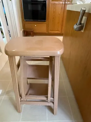 Sale Photo Thumbnail #430: Vintage painted wooden step stool with flip-out steps, showing minor wear and surface marks.