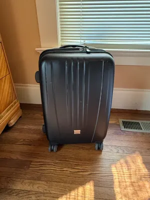 Sale Photo Thumbnail #229: Ricardo Beverly Hills black hardside spinner suitcase with ribbed design, top handle, and four dual wheels.