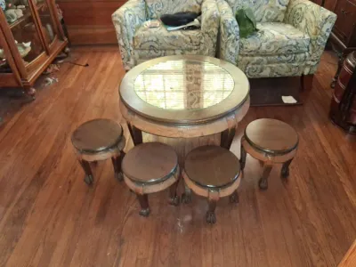 Sale Photo Thumbnail #113: Vintage Asian-style circular coffee table with glass insert top, accompanied by four matching nested round stools featuring carved claw feet.