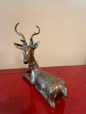 Sale Photo Thumbnail #159: Vintage brass or bronze reclining deer figurine with ornate embossed collar and saddle details.