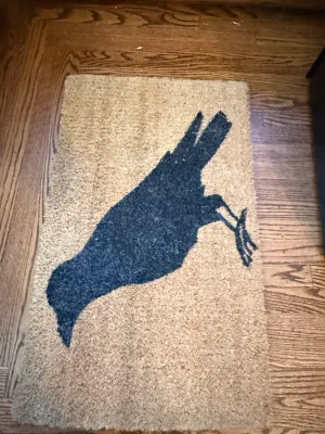 Sale Photo Thumbnail #346: Natural coir doormat featuring a large black crow silhouette design, displayed on hardwood flooring.