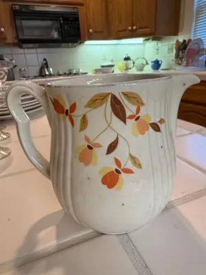 Sale Photo Thumbnail #465: Vintage ceramic water pitcher featuring a ribbed body with hand-painted autumn floral and leaf motifs.
