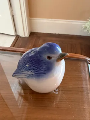 Sale Photo Thumbnail #260: Glazed ceramic bluebird figurine with detailed feather texturing and painted eyes, resting on a glass surface.
